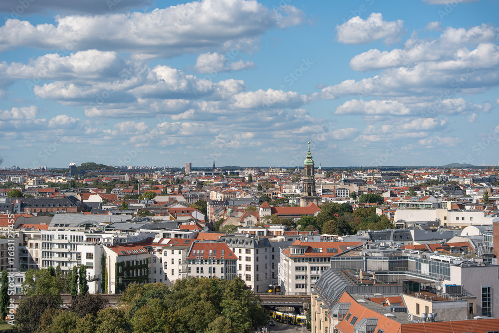Fototapeta premium Cityscape with red roofs and a church steeple in the distance. Historical and modern architecture blend together in the Berlin skyline.