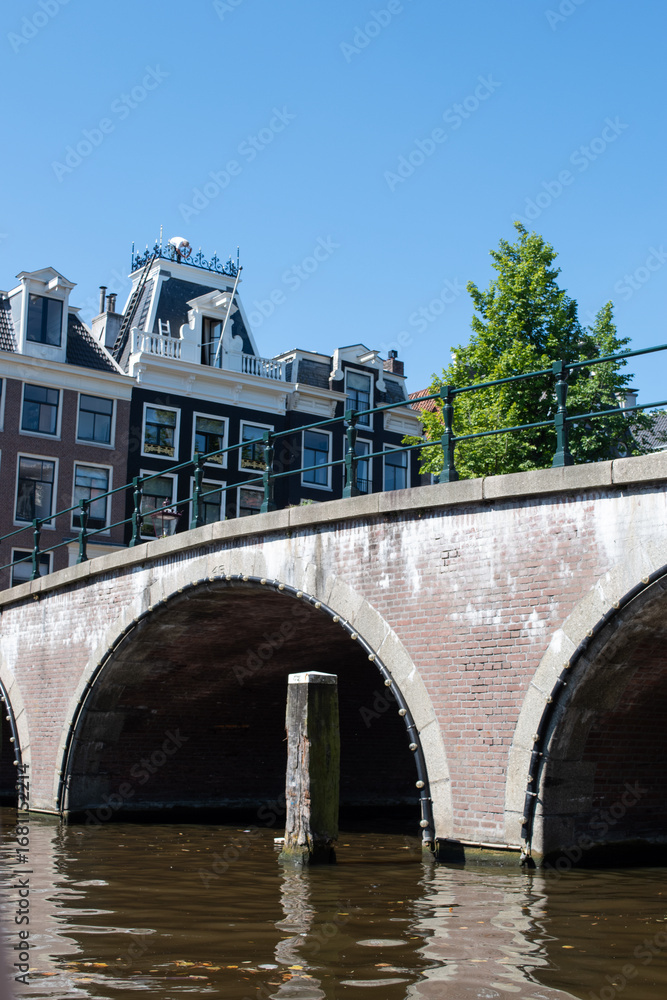 Naklejka premium Beautiful cityscape view of the city of Amsterdam as seen from the canal and bridges.