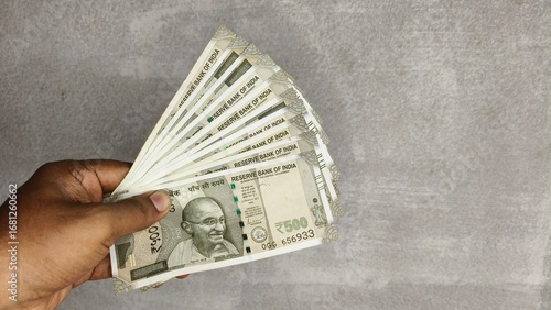 Hand hold Indian new currency 500 rupees bank note isolated on white wall background with copy space. Closeup side view.