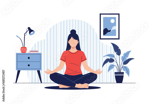 Woman in red t-shirt meditating in lotus position indoors on blue yoga mat next to drawer and lamp