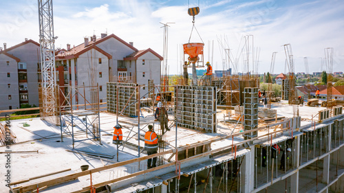 Aerial view on masons fill up vertical mold with help of crane as carry cone tank for cement mixture