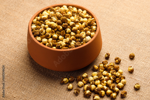 Indian food called roasted Chickpeas or Roasted Chana in mud pot isolated on jute background 