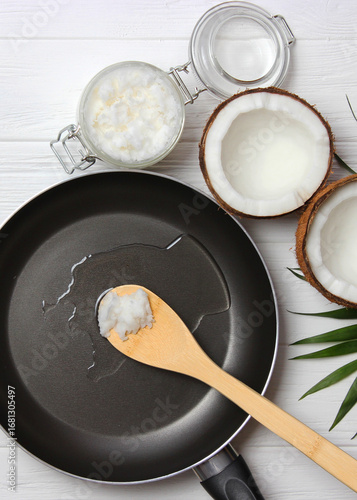 Coconut oil and a frying pan on a wooden table close-up.. Vertical photo format