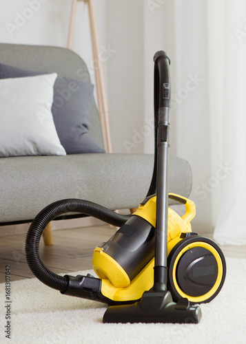 Vacuum cleaner yellow in the interior of the room. Vertical photo format