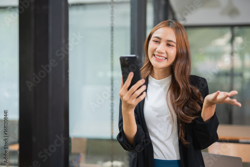 Asian businesswoman in suit using mobile phone while standing in front of modern business building. Free Download Asian businesswoman in suit using mobile phone while standing in front of modern business building. - GFXLoad