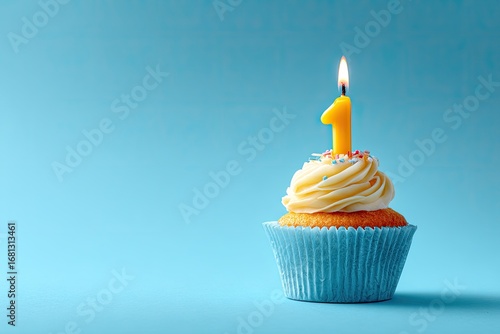 Single cupcake with a lit yellow number one candle on a light teal background