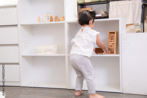 Cuadro en lienzo Asian toddler organizing toys at home, child learning responsibility through cle