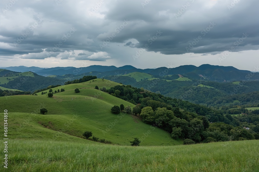 Fototapeta premium Undulating landscapes with multiple ridges extend endlessly. Towering verdant peaks loom beneath a dark, rain-filled sky.