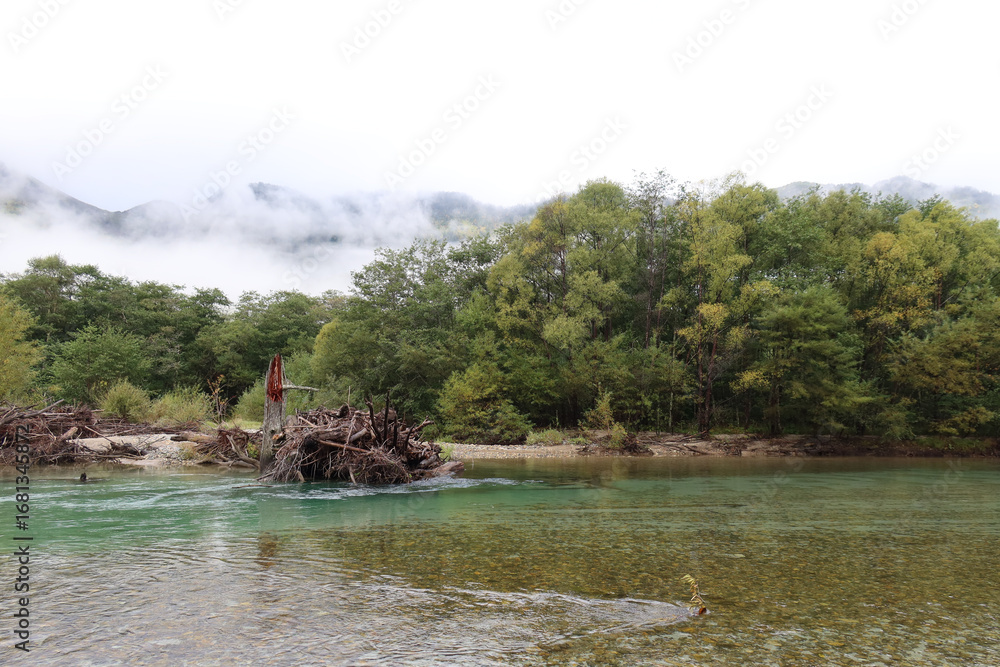 Fototapeta premium Kamikochi, Japan – 5 Oct 2024: scenic view of Northern Japan Alps, featuring Azusa River, lush forests, towering peaks, Kappa Bridge, Myojin Pond, alpine wilderness, Chubu Sangaku National Park.
