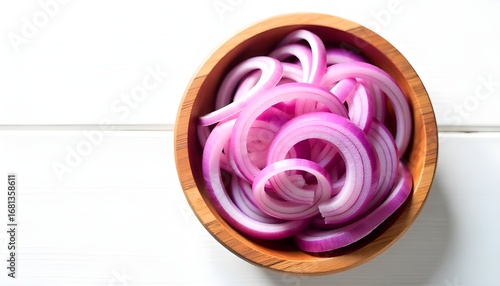 Overhead shot of thinly sliced red onions arranged in a rustic wooden bowl, set against a stark white background. The lighting is bright and even, highlighting the vibrant purple hues of the onions