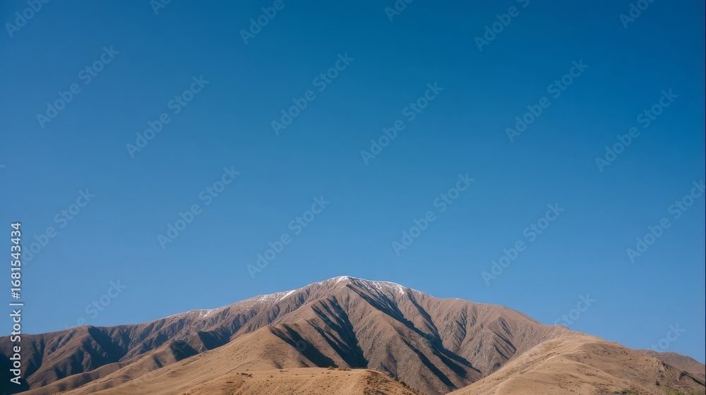 Fototapeta premium Majestic mountain range with rugged ridges transitions from light brown at the base to deep brown at the peaks,