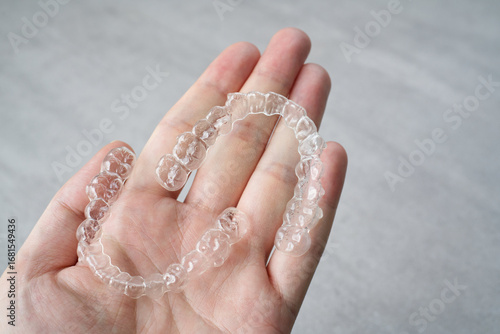 Clear dental aligner in hand. Orthodontic mouthpiece display.