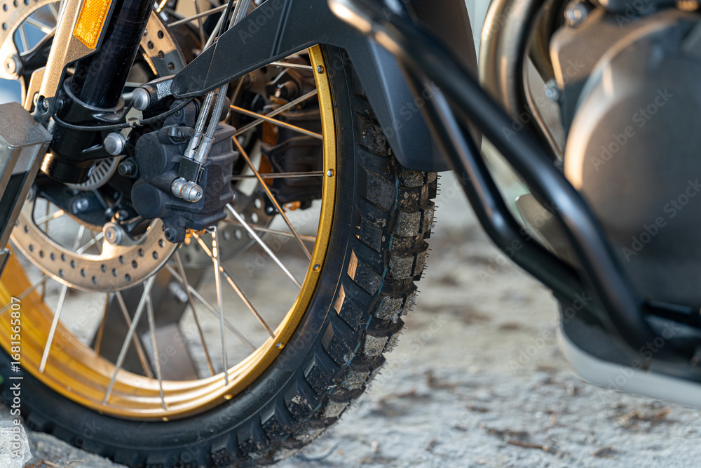 Fototapeta premium Motorcycle close-up showcasing tire, rim, and intricate details in a garage setting during daylight