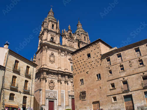 Fotografía Clerecía of Salamanca and House of Shells: A low-angle view of the Pontifical University of Salamanca and a corner of the House of Shells against a clear blue sky