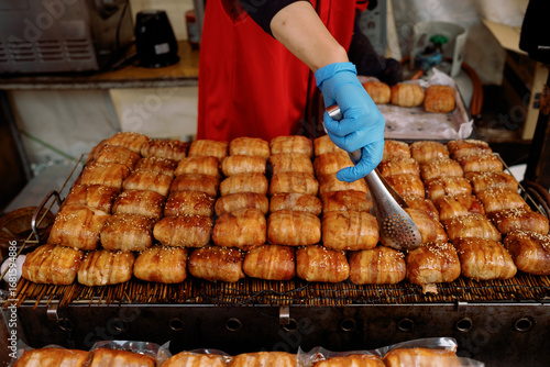 Street vendor grilling delicious bacon wrapped rice cakes at asian market