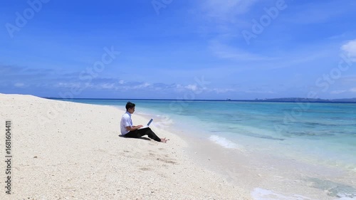 美しいビーチでパソコンを楽しむ笑顔の男性