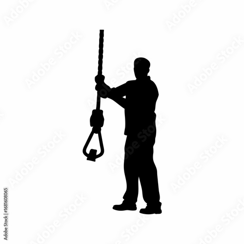 Silhouette of a worker operating a winch for heavy cable installation