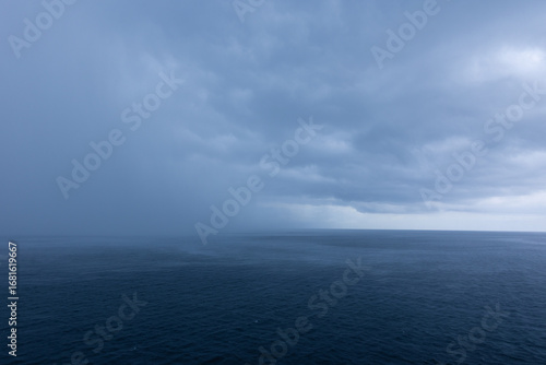 Image of dramatic deep blue ocean horizon on stormy cloudy day rain moving in. Photo taken from deck of cruise ship in the western Caribbean Sea  