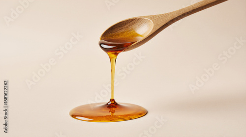 Wooden spoon drizzling honey on a cream background sweet golden minimal food drip concept
