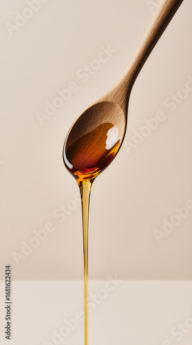 Wooden spoon drizzling honey on a cream background sweet golden minimal food drip concept
