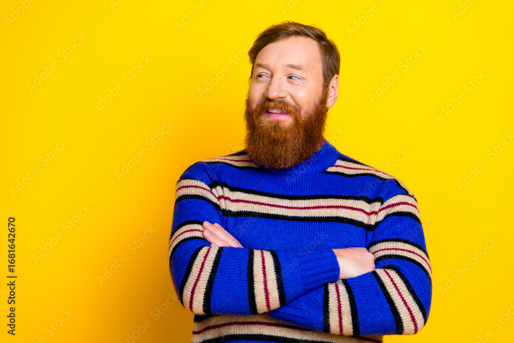 Fototapeta premium Trendy young man with a red beard standing confidently against a bright yellow background in a striped pullover