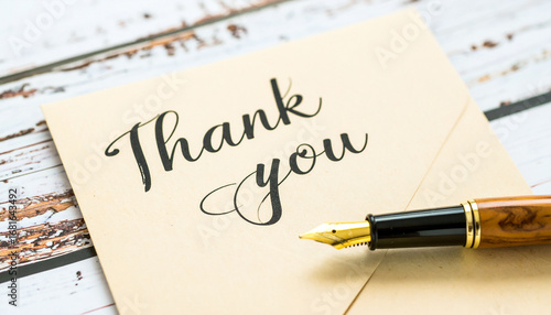 Elegant thank you card with fountain pen on wooden surface