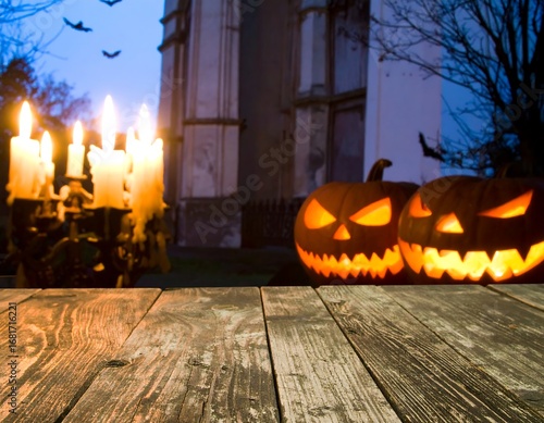 Halloween pumpkins on a wooden table in front of an old church at night