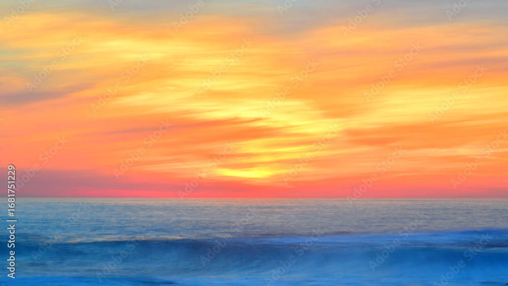 Fototapeta premium Golden sunset enhancing the movement of clouds and waves.