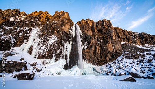 Wallpaper Mural Stunning Frozen Waterfall Amidst Snowy Rocky Cliffs Under a Blue Sky. Torontodigital.ca