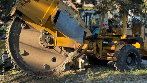 Fotografie Rumbling yellow trencher on grassy terrain unveils secrets of urban archaeology,