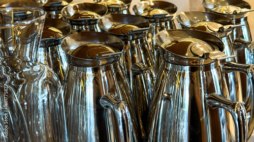 Принти на полотні Glistening chrome carafes stand sentinel in muted cafe light, whispering secrets