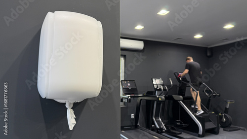 A lone paper towel dispenser watches over a gym scene where a Caucasian man escalates cardio peak, evoking World Health Day vitality