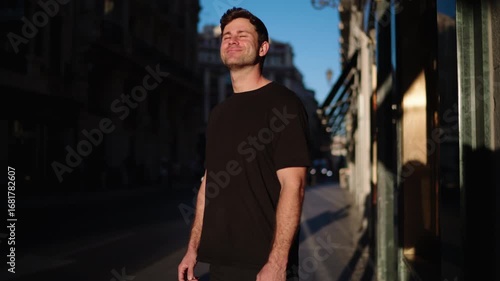Smiling man standing in city street under bright morning sun. Represents positivity, motivation, and joy in modern active lifestyle.
