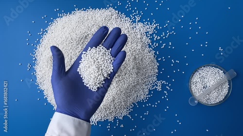 Top view a scientist in a laboratory in blue gloves checks the quality of a batch of white thermoplastic granules. Concept: research, biochemistry, pharmaceutical medicine, plastics plant.