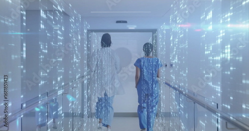 Vászonkép Two staff in scrubs and coat walking toward door in hospital corridor with holog