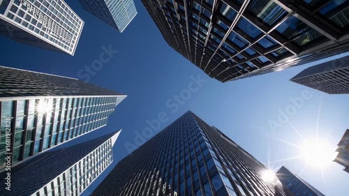 Low-angle wide shot gazing upward at contemporary high-rises in commercial zone on clear day