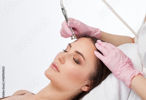 The cosmetologist makes the procedure Microdermabrasion of the face skin of a beautiful woman in a beauty salon.Cosmetology and professional skin care.