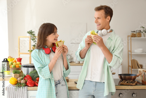 Young couple eating sandwic...