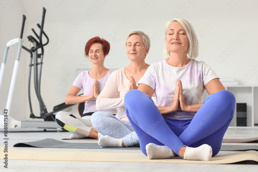 Obraz premium Sporty mature women practicing yoga at gym