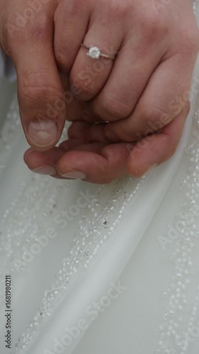 Romantic close up of newlywed couple holding hands, showing wedding ring and elegant attire, symbolizing love, unity and marriage ,vertical video