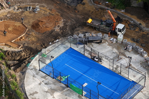 Construction site with workers, truck and new blue sports ground, aerial view  
