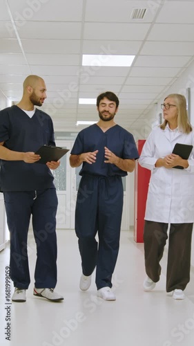 Vertical video of medical professionals, doctors, and nurses collaborating and discussing patient information in a hospital hallway. Nurses collaborating and discussing patient information