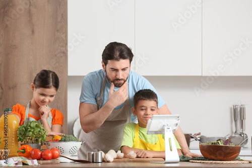 Family cooking together in kitchen, father and children learning healthy reci...