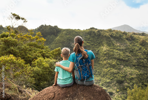 Fototapeta Mother and son enjoy a vibrant view during a hiking adventure in green hills