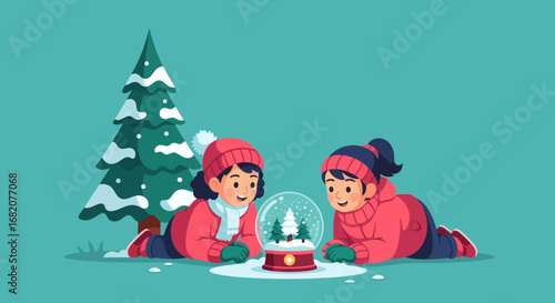 Two girls in winter clothes lie down looking at a snow globe with miniature trees next to a snowcovered pine tree