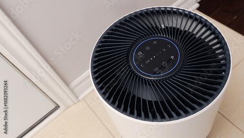 Close up view of Air Purifier with Black Fan. Black Round Electronic Device with Buttons and Bright Lights on White Background