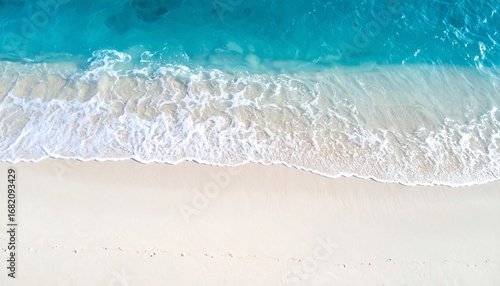 Fototapeta Naklejka Na Ścianę i Meble -  Aerial view of white sand beach and turquoise water with waves gently lapping the shore.