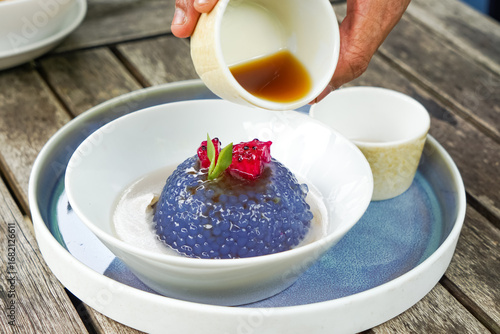 Kuih Sagu Melaka Bunga Telang, a traditional Malaysian dessert made with blue butterfly pea-infused tapioca pearls, served with palm sugar syrup and coconut milk.
