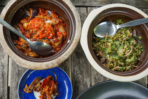 A flavorful assortment of side dishes served with rice, including spicy red snapper in tamarind gravy, crispy fried chicken, stir-fried chili eggplant, rich beef rendang, and seasoned vegetable salad.
