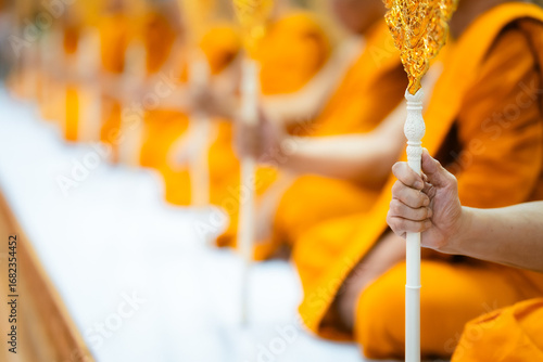 Wallpaper Mural A close-up of a monk's hand holding a ceremonial staff with other monks in the background, blurred. Torontodigital.ca
